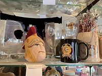 Front view of lot showing two balloon goblets, plush Trojan head, Hard Rock pint glass, Elks stem glass, USC mug