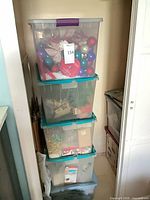 Stack of five translucent plastic tubs filled with Christmas decorations