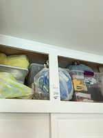 Upper cabinet showing two large clear bins and additional bags of decorations