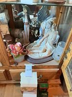 Cabinet view with Pietà, male figurine, rose, vase, Lladro box