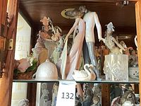 Shelf with multiple Lladró figurines including couple, dancers, swans, crystal tumbler
