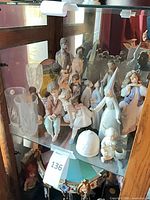 Shelf displaying multiple Lladro figurines and clear glass vases