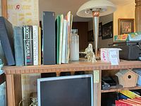 Top shelf showing binders, books, lamp, angel figurine, birdhouse and part of printer
