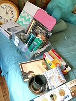 Overall lot on bed showing multiple items including tote, mugs, appliance boxes, framed mat