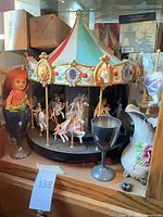 Cabinet view showing carousel, doll, goblet, pitcher, ornament box