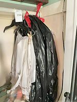 Group of three garments on hangers: white floral wrap, black plastic-covered hanger, beige and grey blazers