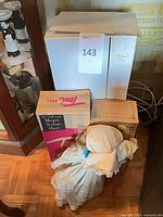 Stacked boxes and one large Madame Alexander style doll on floor; shows quantity and packaging