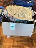 Box containing multiple handbags with straw bag on top