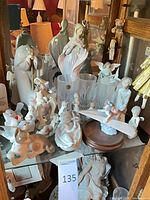 Overview of cabinet shelf showing majority of Lladró porcelain figurines and glass vases