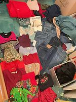 Pile of jeans, sweaters, shirts, assorted clothing on floor