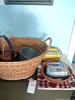 Overview of lot showing large wicker basket containing smaller items plus wooden bowl and plastic container