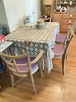 Dining table with lace covering and four chairs around