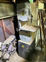 Full view of band saw on stand next to other items