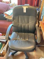 Front view of black leather office chair with armrests and wheeled base