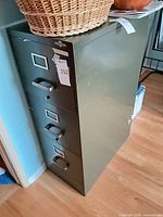 Full view of olive green metal four-drawer cabinet showing drawers and pulls