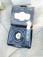 Stove in open carrying case showing burner and controls