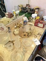 Overview of sink counter with pressed glass pieces, ceramic figurine, green bowls and Bobby McGee's bowl