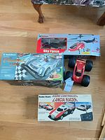 All four radio-controlled toys grouped: two boxed RadioShack cars, boxed Sky Force helicopter, loose red monster truck
