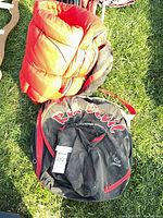 Black circular Red Devil carrying case with red handles lying on grass