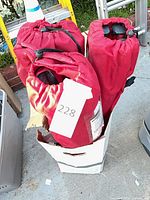 Three red folding chairs in carry bags inside cardboard box