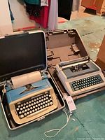 Royal blue and beige manual typewriter in case next to another machine