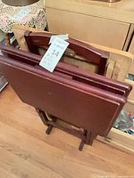 Stacked view of three folded mahogany TV trays