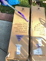 Two cardboard boxes containing the folded red chairs