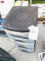 Overall view of black plastic organizer with four translucent drawers showing wear