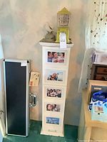 Full view of tall narrow white cabinet with photo frames on front