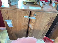 Front view of cabinet showing two doors, knob, wood grain finish, wear