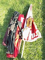 Folded USC umbrella, red chair bag, black folding frame grouped on grass