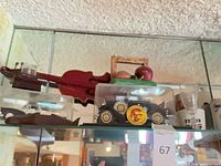 Shelf view showing red miniature violin, USC convertible car in case, tabletop USC display, partial shot glass
