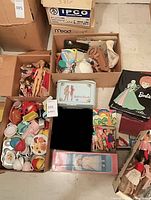 Group view of dolls, lunchbox, binder, play dishes, accessories