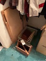 Closet area showing plastic tote with wooden cases and open wooden box