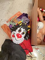 Floor view of inflatable Sylvester mask, costume fabric, box edge with doll parts visible