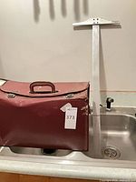 Exterior view of burgundy attache case showing handle, latches and overall wear