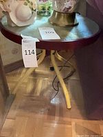 Full view of round wood side table with yellow metal legs