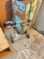 Hand truck folded flat against floor showing platform and wheels