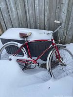 Side view of entire bicycle in snow against fence