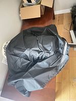 Folded black side of two-tone nylon fire pit cover on table