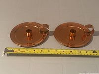 Top view of both copper candle holders with tape measure showing diameter