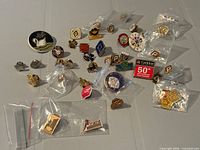 Overview of 35 assorted lapel pins on table, many in small plastic bags