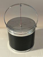 front view showing black faux leather body, chrome lid with handle up