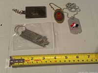 All four metal key rings/dog tags with measuring tape for scale