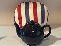 Teapot in front of striped tea cozy