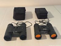 Two compact binoculars with cords and pouches displayed