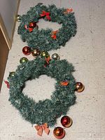 Both artificial wreaths on floor showing size and attached ornaments