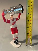 Front view showing full figurine and measuring tape indicating height