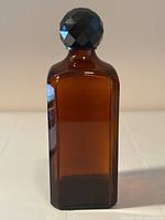 Front view of amber glass liquor bottle with black faceted stopper