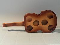 Full view of wooden violin-shaped tray with six holes